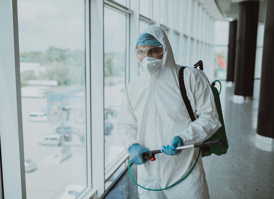Abatement Contractor Insurance - Abatement Worker in a Protective Suit with Mask Sprays for Mold in the Office