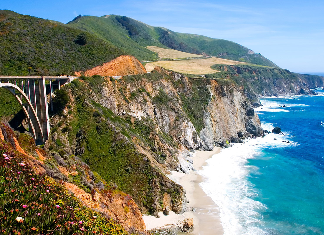 Insurance Solutions - Aerial View of Bridge in Big Sur, California on a Sunny Day With Blue Crashing Waves